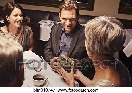 Stock Photo - Caucasian man giving woman gift in restaurant. Fotosearch