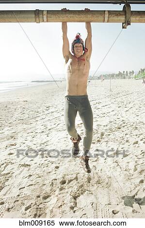 Stock Photography - Caucasian man hanging from pipe. Fotosearch