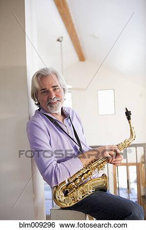 Caucasian man holding saxophone View Large Photo Image Stock Photograph - Caucasian man holding saxophone. Fotosearch