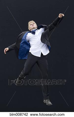 Stock Image - Caucasian man in suit jumping in mid-air. Fotosearch