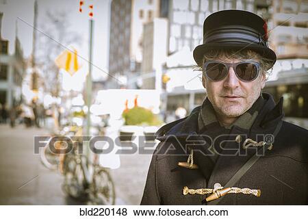 Stock Photo - Caucasian man in top hat standing on city sidewalk. Fotosearch