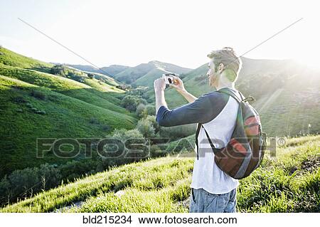 Picture - Caucasian man photographing scenic view from rural hilltop. Fotosearch