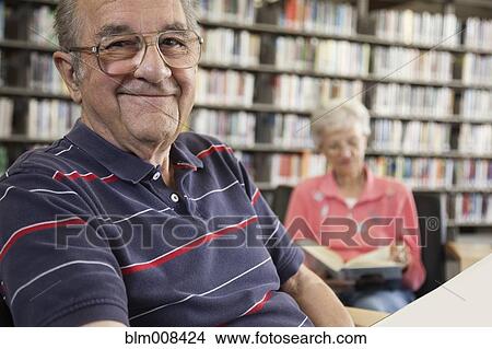 Picture - Caucasian man reading book in library. Fotosearch