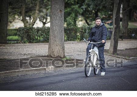 Stock Photography - Caucasian man riding bicycle on street. Fotosearch