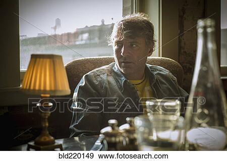 Stock Photo - Caucasian man sitting at table near window. Fotosearch
