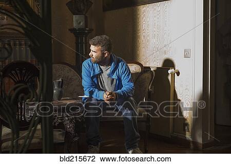 Caucasian man sitting in sunlight in living room View Large Photo Image Stock Image - Caucasian man sitting in sunlight in living room. Fotosearch