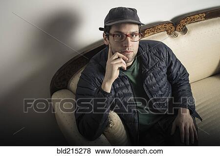Caucasian man sitting on sofa View Large Photo Image Stock Photo - Caucasian man sitting on sofa. Fotosearch