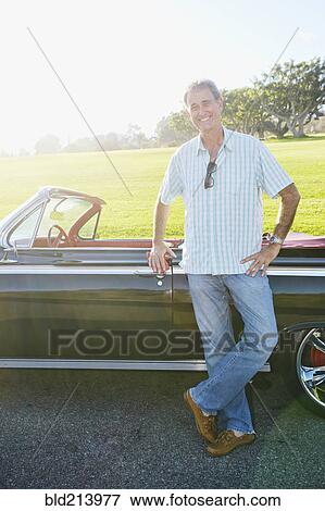 Stock Photo - Caucasian man smiling near classic convertible. Fotosearch