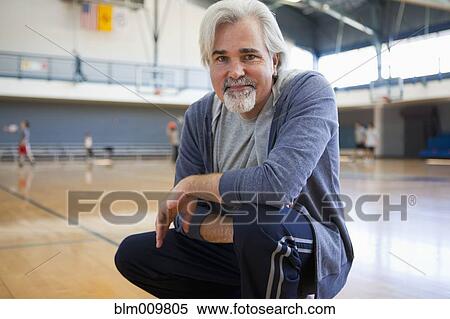 Stock Photography - Caucasian man squatting in gym. Fotosearch