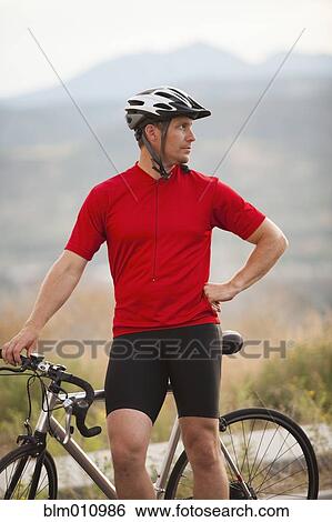 Stock Photograph - Caucasian man standing near bicycle. Fotosearch