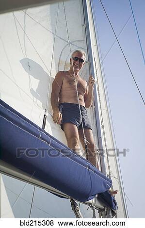 Stock Photo - Caucasian man standing on boat sail. Fotosearch