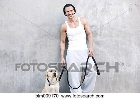 Stock Image - Caucasian man standing with dog. Fotosearch