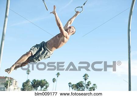 Caucasian man swinging on gymnastic rings View Large Photo Image Stock Photo - Caucasian man swinging on gymnastic rings. Fotosearch