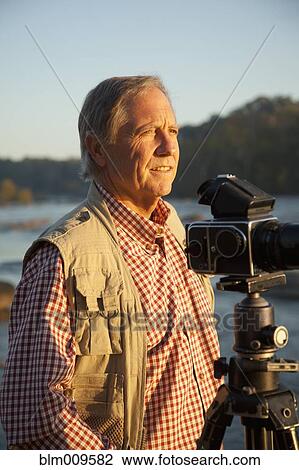 Stock Image - Caucasian man taking photographs on beach. Fotosearch