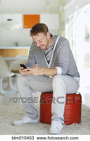 Caucasian man text messaging on cell phone in living room View Large Photo Image Stock Image - Caucasian man text messaging on cell phone in living room. Fotosearch