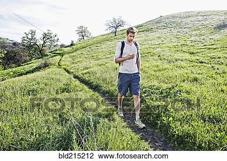 Caucasian man using cell phone on dirt path View Large Photo Image Stock Image - Caucasian man using cell phone on dirt path. Fotosearch