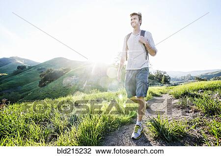 Stock Image - Caucasian man walking on dirt path. Fotosearch