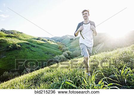 Stock Photograph - Caucasian man walking on rural hillside. Fotosearch