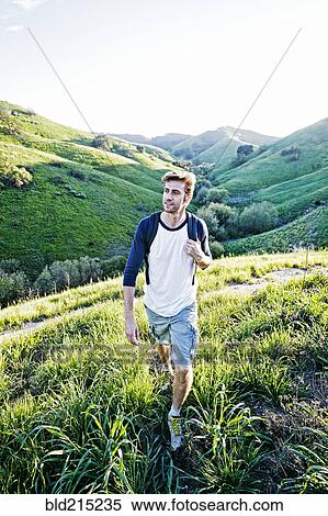 Stock Photography - Caucasian man walking on rural hillside. Fotosearch