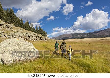Caucasian men and boy hiking in grassy remote landscape View Large Photo Image Stock Photo - Caucasian men and boy hiking in grassy remote landscape. Fotosearch