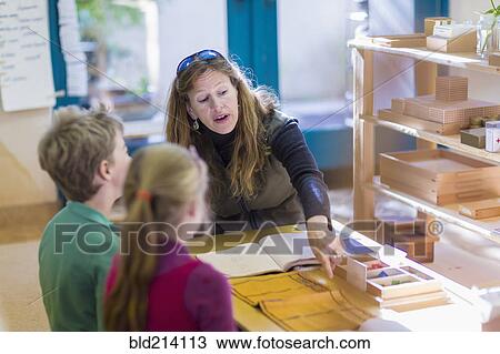 Caucasian Montessori teacher helping students in classroom View Large Photo Image Stock Image - Caucasian Montessori teacher helping students in classroom. Fotosearch