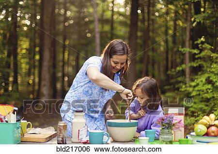 Stock Photograph - Caucasian mother and daughter cooking in forest. Fotosearch