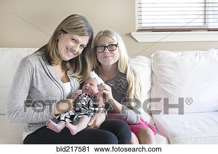 Caucasian mother and daughter cuddling newborn on sofa View Large Photo Image Stock Image - Caucasian mother and daughter cuddling newborn on sofa. Fotosearch