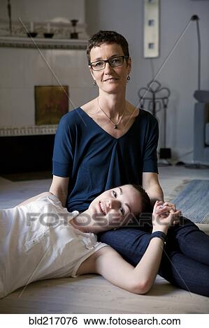 Stock Photograph - Caucasian mother and daughter hugging on floor. Fotosearch