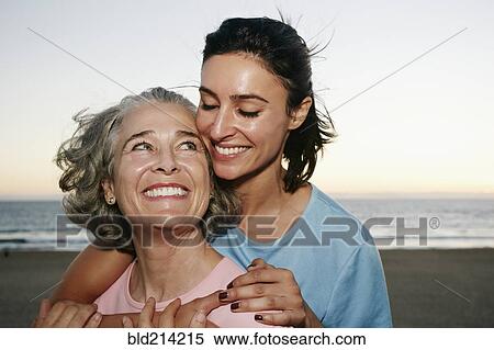 Stock Photography - Caucasian mother and daughter hugging at beach. Fotosearch