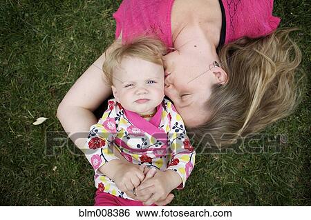 Stock Photograph - Caucasian mother and daughter laying in grass. Fotosearch