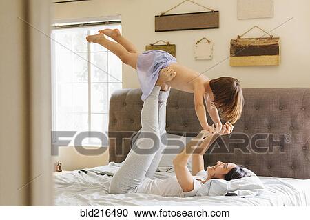Caucasian mother and daughter playing on bed View Large Photo Image Stock Image - Caucasian mother and daughter playing on bed. Fotosearch