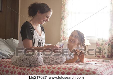 Stock Photo - Caucasian mother and daughter playing cards in bedroom. Fotosearch