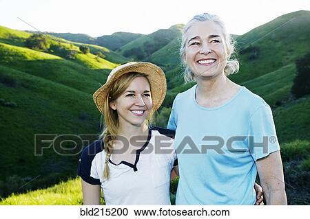 Stock Image - Caucasian mother and daughter smiling on rural hilltop. Fotosearch