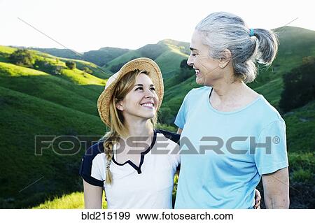 Stock Photo - Caucasian mother and daughter smiling on rural hilltop. Fotosearch