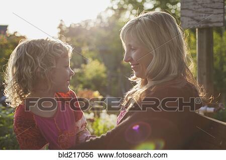 Stock Photograph - Caucasian mother and daughter smiling in garden. Fotosearch