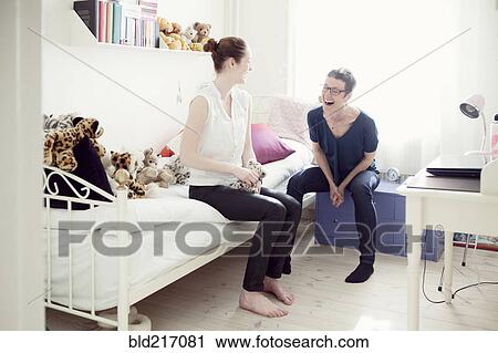 Stock Image - Caucasian mother and daughter talking in bedroom. Fotosearch