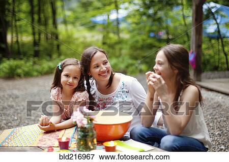 Stock Photo - Caucasian mother and daughters sitting outdoors. Fotosearch
