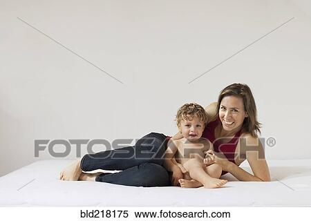 Stock Photography - Caucasian mother and son laying on bed. Fotosearch
