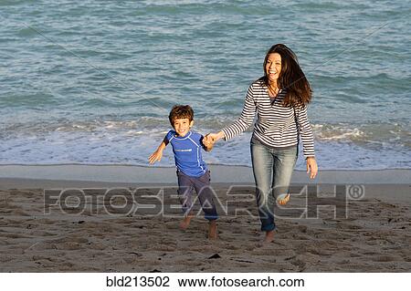Stock Image - Caucasian mother and son playing on beach. Fotosearch