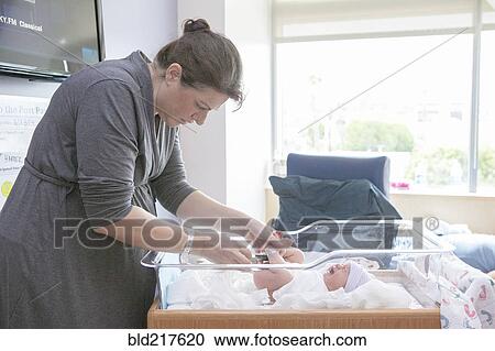 Caucasian mother changing newborn daughter in hospital crib View Large Photo Image Stock Image - Caucasian mother changing newborn daughter in hospital crib. Fotosearch