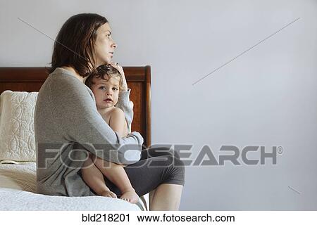 Stock Image - Caucasian mother hugging son on bed. Fotosearch