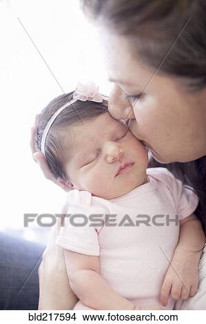 Picture - Caucasian mother kissing baby girl. Fotosearch