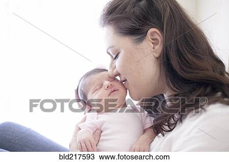 Stock Image - Caucasian mother kissing baby girl. Fotosearch