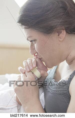 Picture - Caucasian mother kissing foot of newborn daughter. Fotosearch