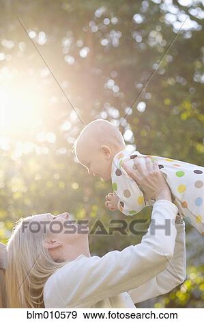 Caucasian mother lifting baby outdoors View Large Photo Image Stock Photo - Caucasian mother lifting baby outdoors. Fotosearch