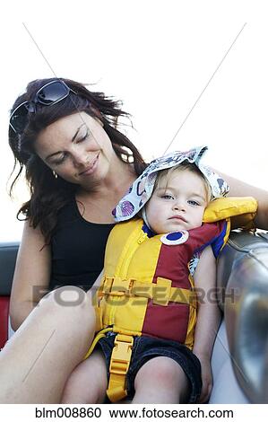 Stock Image - Caucasian mother looking at daughter wearing life jacket. Fotosearch
