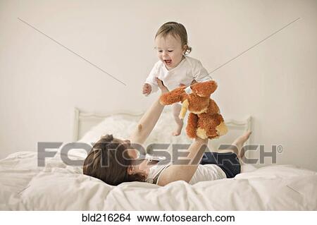 Caucasian mother playing with baby on bed View Large Photo Image Picture - Caucasian mother playing with baby on bed. Fotosearch