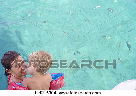 Picture - Caucasian mother teaching son to swim in pool. Fotosearch
