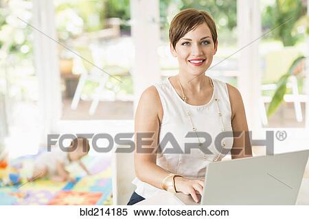 Caucasian mother using laptop at counter View Large Photo Image Stock Photography - Caucasian mother using laptop at counter. Fotosearch