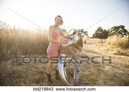 Stock Image - Caucasian musician carrying tuba on dirt path. Fotosearch